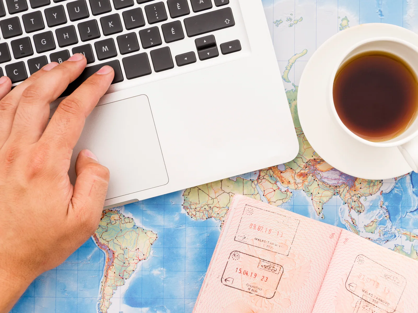 Notebook, passaporte e caderno sobre uma mesa